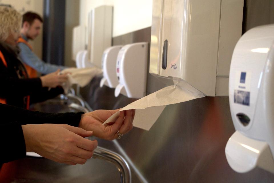 Hænder der trækker hvidt papir ud af en hvid dispenser