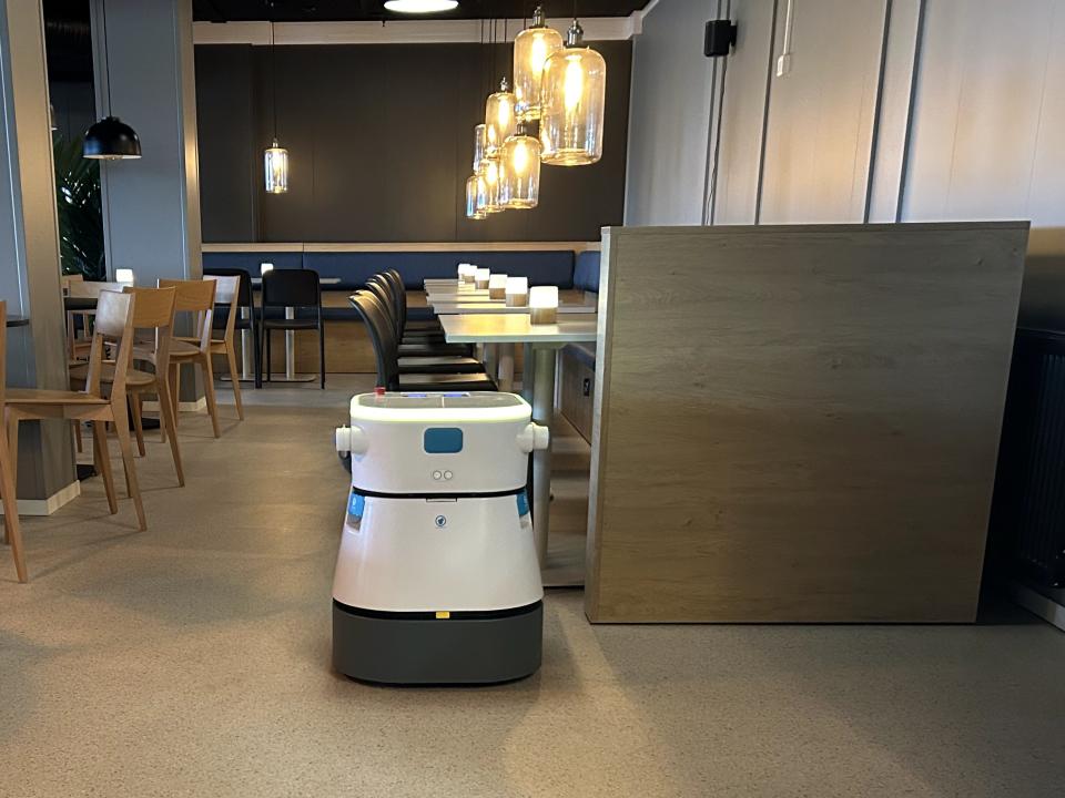 Rengøringsrobot kører rundt i spiseområde på hotel.